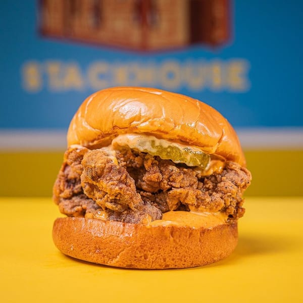 A Stack House fried chicken sandwich with pickles and sauce on a brioche bun.